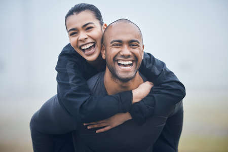 Shes my ultimate supporter. Shot of a young male athlete giving his girlfriend a piggyback ride.の写真素材
