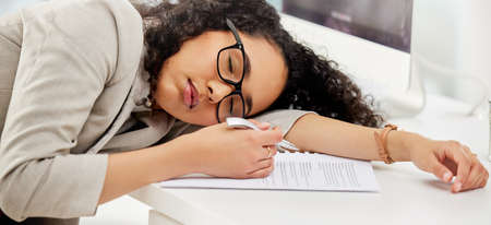 All this filing is so dreadfully boring. Shot of a young businesswoman sleeping at her desk in an office.の写真素材