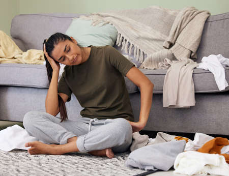 When does the laundry end. Shot of a young woman looking tired while cleaning at home.