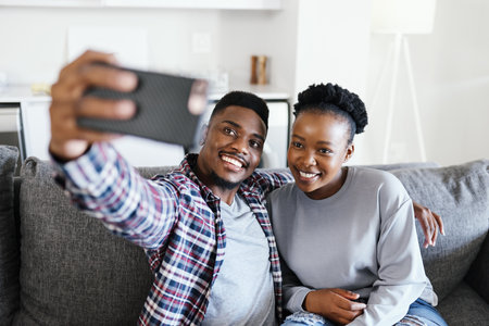 Simple moments turned into beautiful memories. Shot of a young couple taking selfies together at home.の写真素材