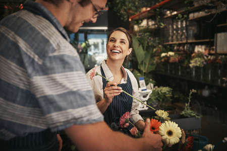 Flowers brighten up any day. Cropped shot of two young florists working together inside their plant nursery.の写真素材