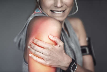 She strained her shoulder with that workout. Cropped shot of a young woman holding her injured...
