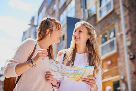 We better not get lost. Low angle shot of two attractive young girlfriends reading a map while exploring a foreign city.の写真素材