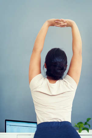 Making sure she gets good circulation. Rearview shot of a young businesswoman stretching while...