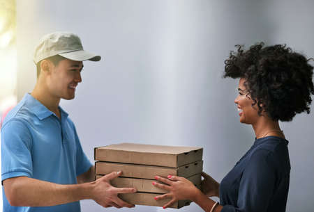 Careful, these are still hot. Shot of a happy businesswoman accepting a pizza delivery from a...