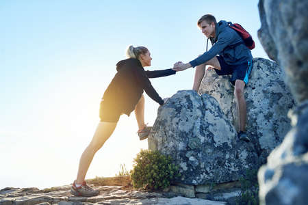 Lemme give you a hand. Full length shot of a young man helping his girlfriend while hiking.の写真素材
