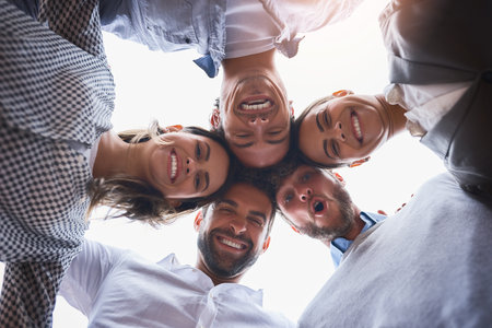 We make one dynamic team. Low angle shot of a group of businesspeople huddled together on their...