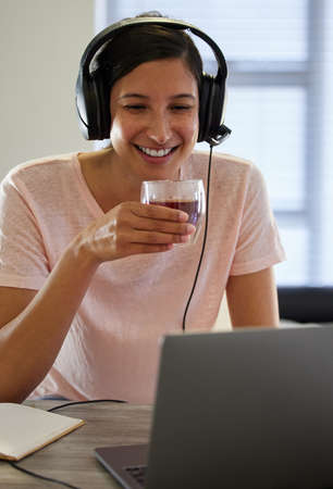 Today is a great day for some fresh knowledge. Shot of a young woman drinking tea while working from home.の写真素材