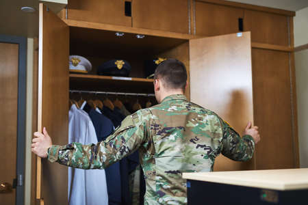 Discipline is a choice made daily. Shot of a young soldier standing getting dressed in the dorms of a military academy.の写真素材