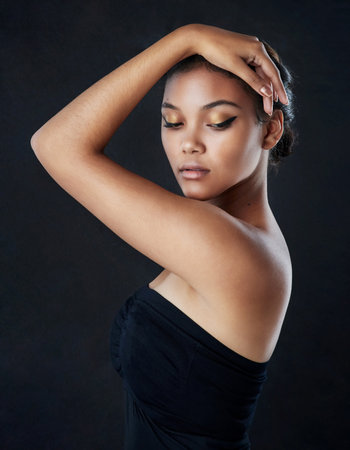 Shes a piece of paradise. Shot of a beautiful woman posing against a black background.の写真素材