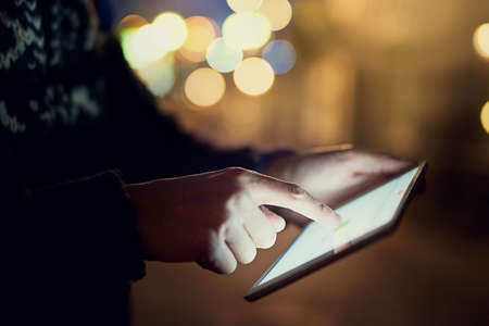 Connected in the city. Shot of an unrecognizable young man looking at photographs on his tablet while on vacation.の写真素材
