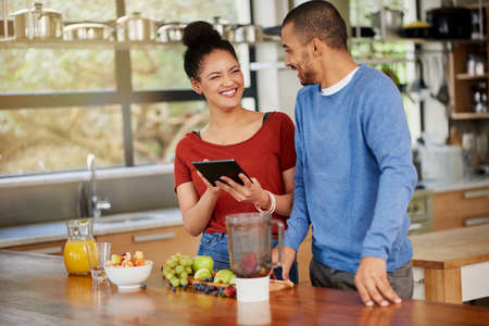 Downloading a dieting app designed for couples. Shot of a happy young couple using a digital tablet...