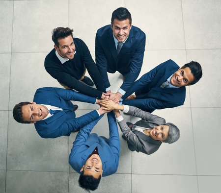 Fuelling greatness together. Portrait of a group of businesspeople joining their hands together in unity.の写真素材
