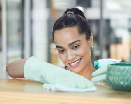 Dust wont win in this house. Shot of a young woman cleaning a surface at home.の写真素材