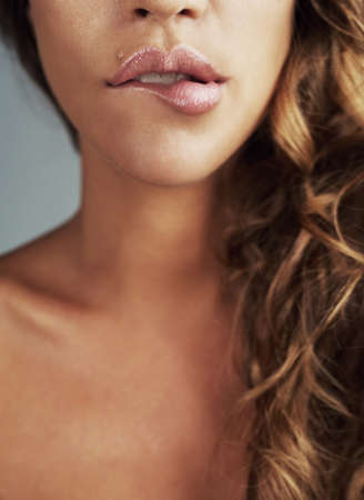 Love your lips. Cropped shot of a young woman biting her lips.の写真素材