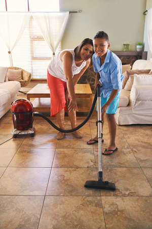 Hes quite helpful around the house. Portrait of a mother and son vacuuming the floor.の写真素材