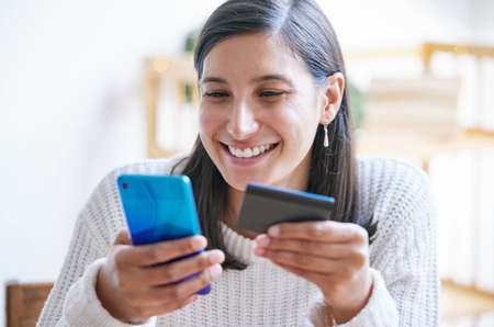 Theres a lot youll only find online. Shot of a young woman using a laptop and credit card in her...