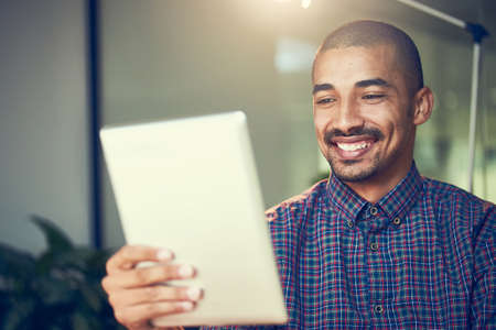 Getting in some overtime. Cropped shot of a young designer working late on a digital tablet in an...