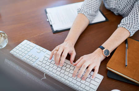 Those deadlines need your attention. High angle shot of an unrecognisable businesswoman working on a computer in an office.の写真素材