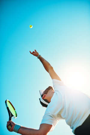 You got served. Low angle shot of a sporty young man playing tennis.の写真素材