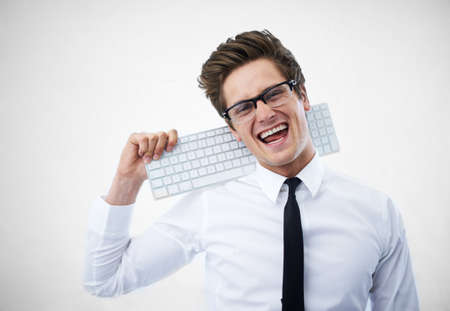Up to date with all technology. A young nerdy guy resting his keyboard on his shoulder.の写真素材