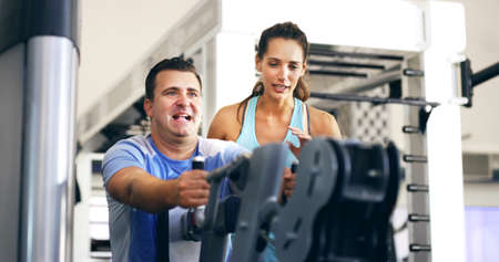 Give me a few more. Cropped shot of a female fitness instructor taking her male client through a...