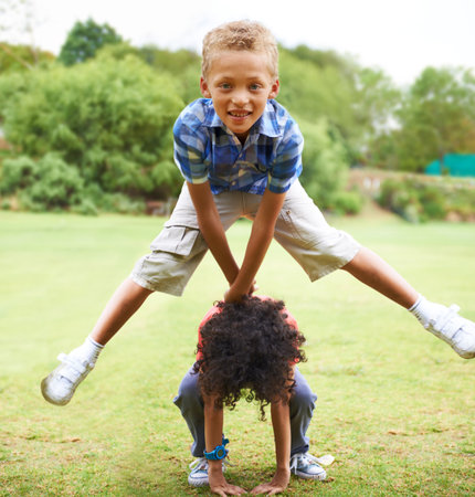 Leapfrogging. A young boy doing a leapfrog over his friends back.