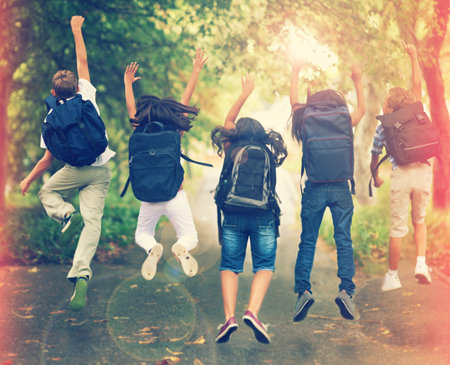 Spring break. Rearview shot of a group of school children jumping in the air.の写真素材