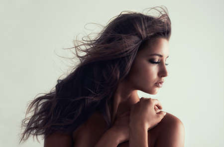 Simple is beautiful. Studio shot of a gorgeous young woman posing topless against a grey background.