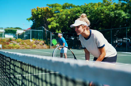 Leave it all on the court. Cropped shot of a mixed doubles tennis team playing together on a tennis court outdoors.の写真素材