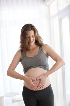 Waiting for the arrival. Cropped shot of a young pregnant woman standing in her home.