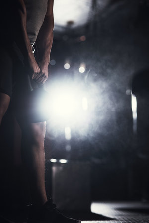 Watch me gain more and more. Closeup shot of an unrecognisable man exercising with a kettlebell in a gym.の写真素材