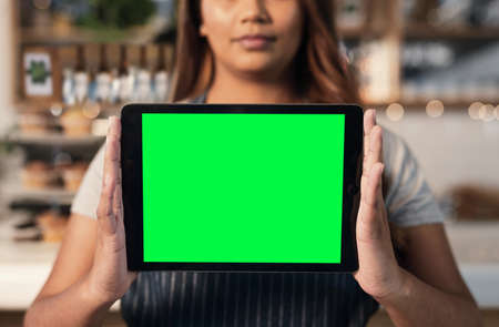 Market yourself so you can stand apart from your competitors. Closeup shot of an unrecognisable woman holding a digital tablet with a green screen in a cafe.の写真素材