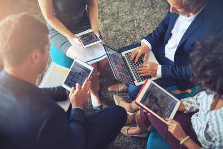 Technology has changed the geography of the office completely. High angle shot of a group of businesspeople using their digital tablets.の写真素材