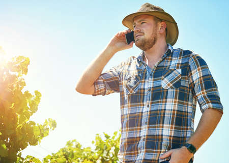 Getting some advice from a fellow farmer. Shot of a farmer talking on his phone while out in a...