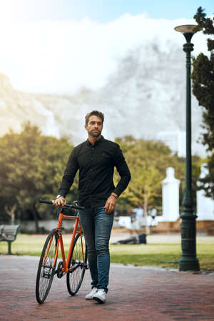 Stopping in the park. Full length shot of a handsome young man traveling with his bike through the...