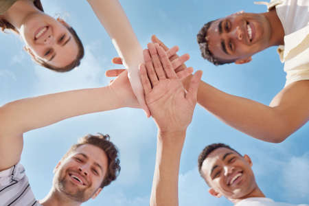 Friends on three. Low angle shot of a group of young people stacking their hands.