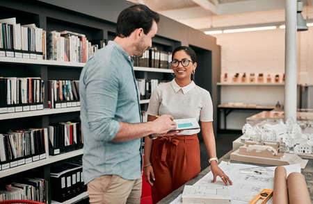 Weve completed more designs than we thought we would. Cropped shot of two aspiring young architects working together in a modern office.の写真素材