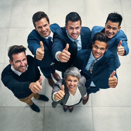 We all approve. Portrait of a group of businesspeople showing thumbs up together in an office.の写真素材