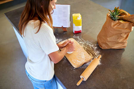 Home made is best. A young woman kneading dough in her kitchen.