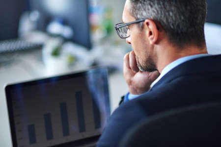 Technology keeps him current and connected. Shot of a businessman using a laptop in the office.