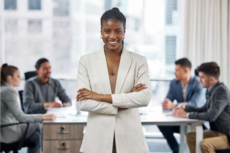 You can call me boss lady. Shot of a young businesswoman standing with her arms crossed in a meeting...