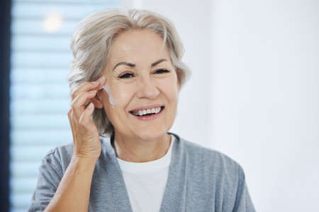 This keeps me looking young. Shot of a senior woman going through her skincare routine at home.