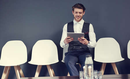 Last minute checks before the interview. Shot of a young businessman using a tablet while waiting...