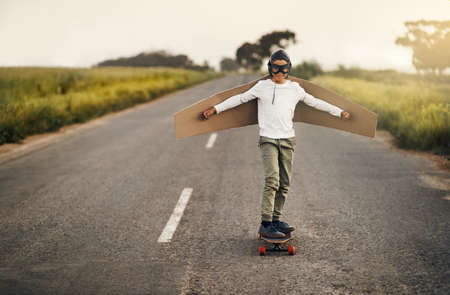 This skater knows how to soar. Shot of a young boy pretending to fly with a pair of cardboard wings...