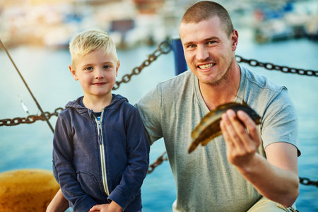 Catching their own dinner. Portrait of a father and his little boy fishing together at the harbor.の写真素材