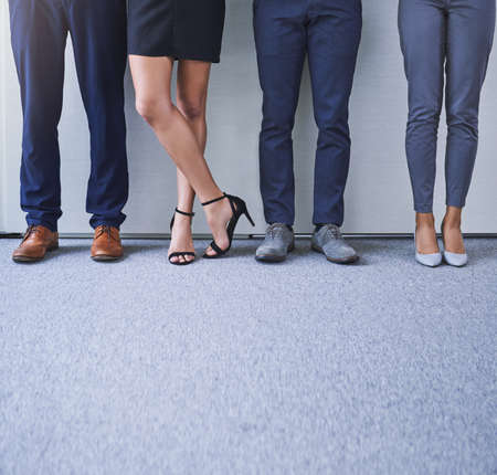 Strive for success and success will stay in your stride. Closeup shot of a group of unrecognizable businesspeople standing in line against a grey background.の写真素材