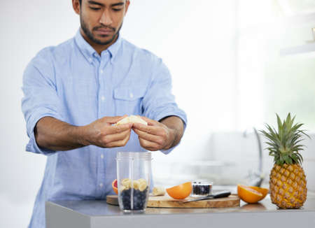 Theres only one way to start the day. Shot of a man making himself a smoothie at home.の写真素材