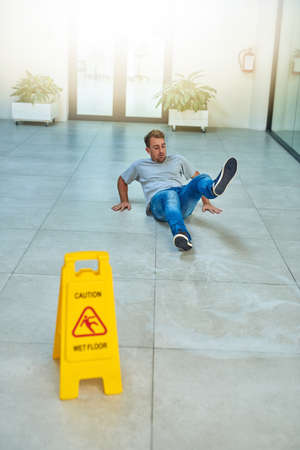 He didnt read the sign. Shot of a man cleaning an office building.の写真素材