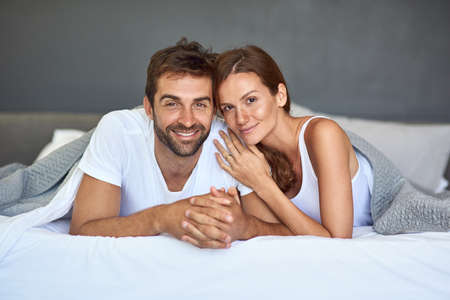 Keep love close to home. Shot of a happy young couple relaxing in bed together at home.